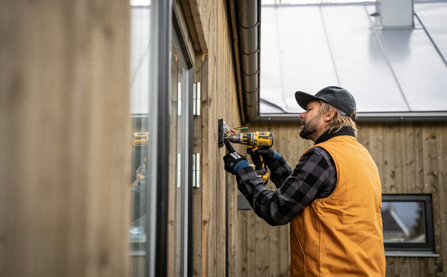 An electrician installing an electrical box on the outside of a house
