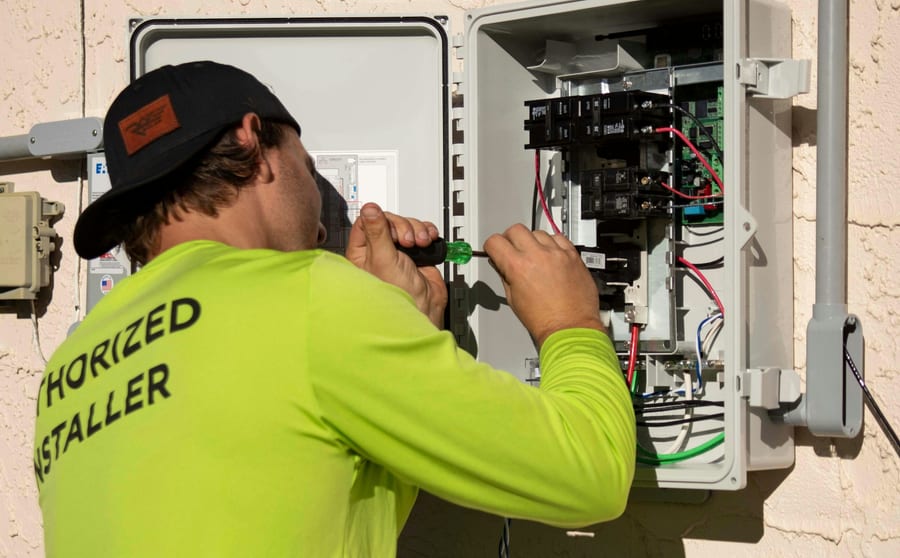 An electrician working inside an open electrical enclosure